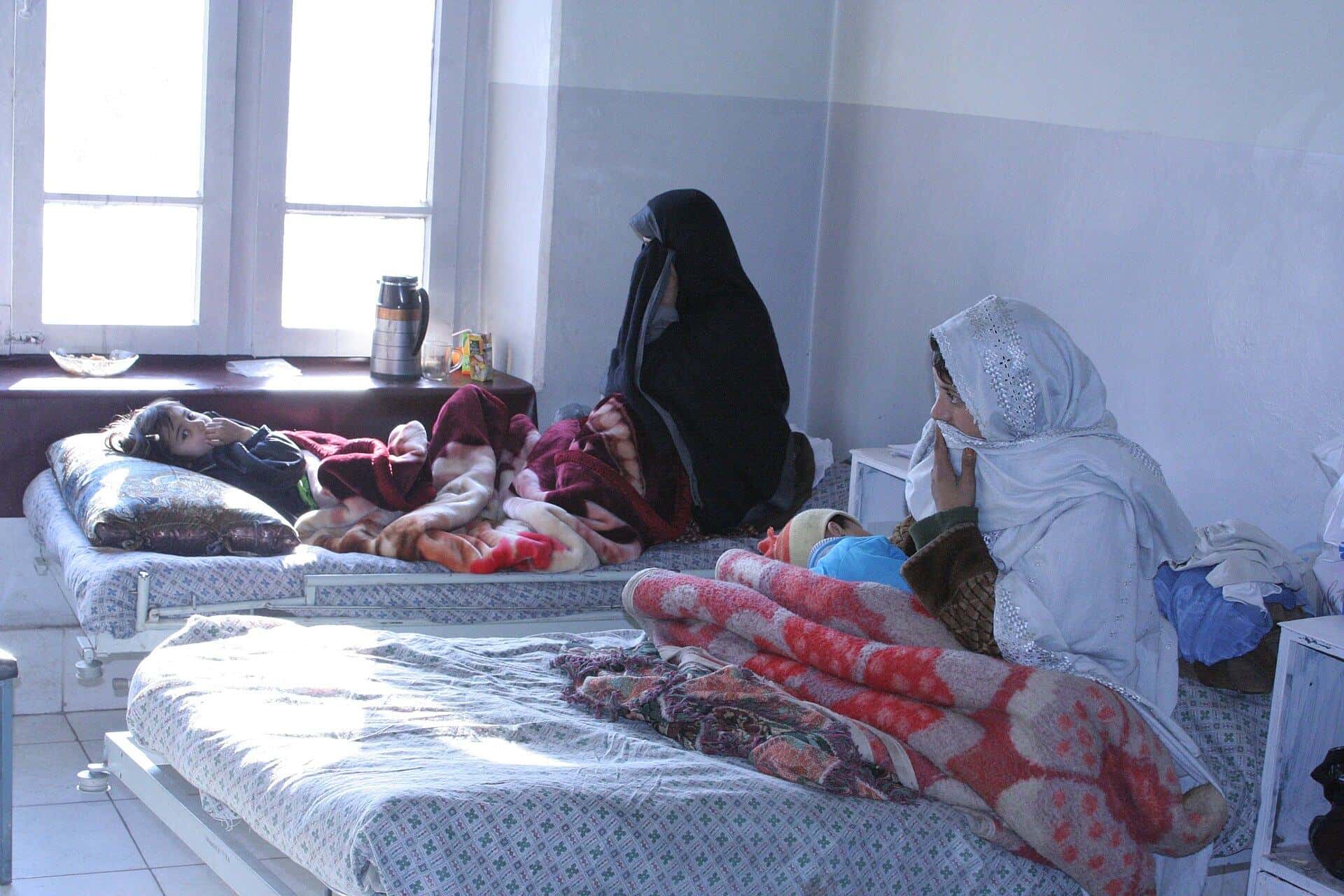 Mothers and children resting on beds in a hospital recovery room in Kabul