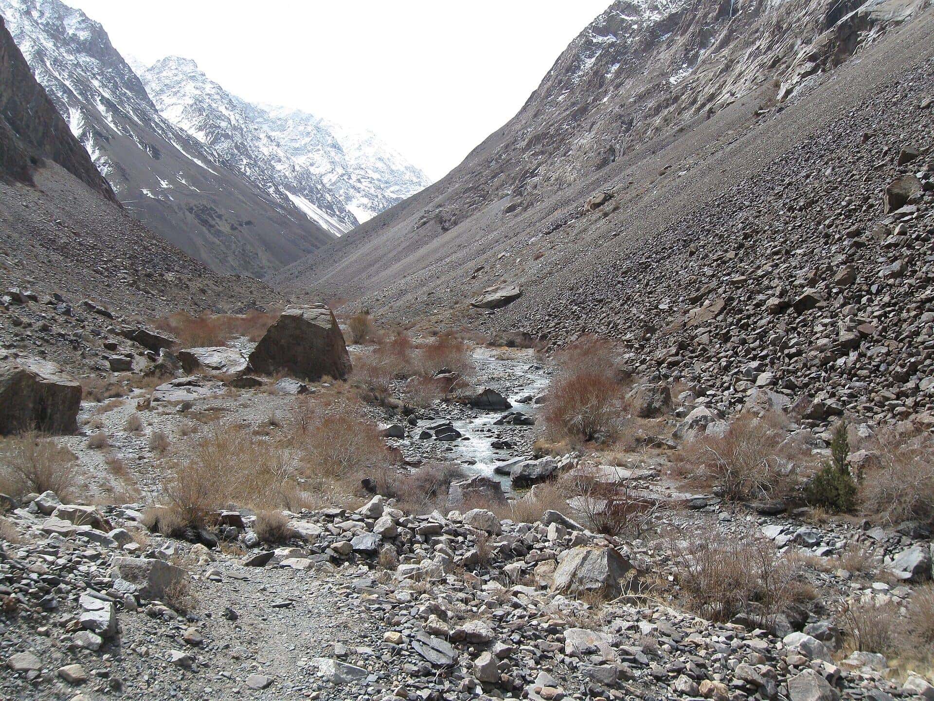 A rocky river valley between snowy mountains